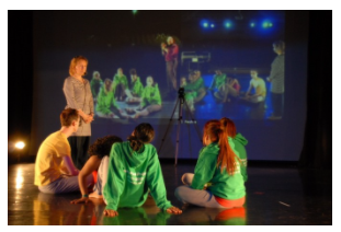 Live International Telematic Performance with Florida State University - Image displaying student sat on floor with tutor standing.